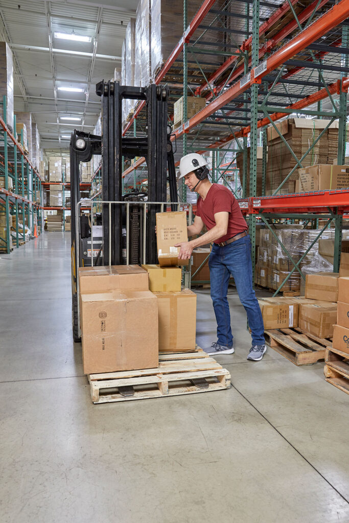 Warehouse worker picks packages on a pallet using Voice Picking technology