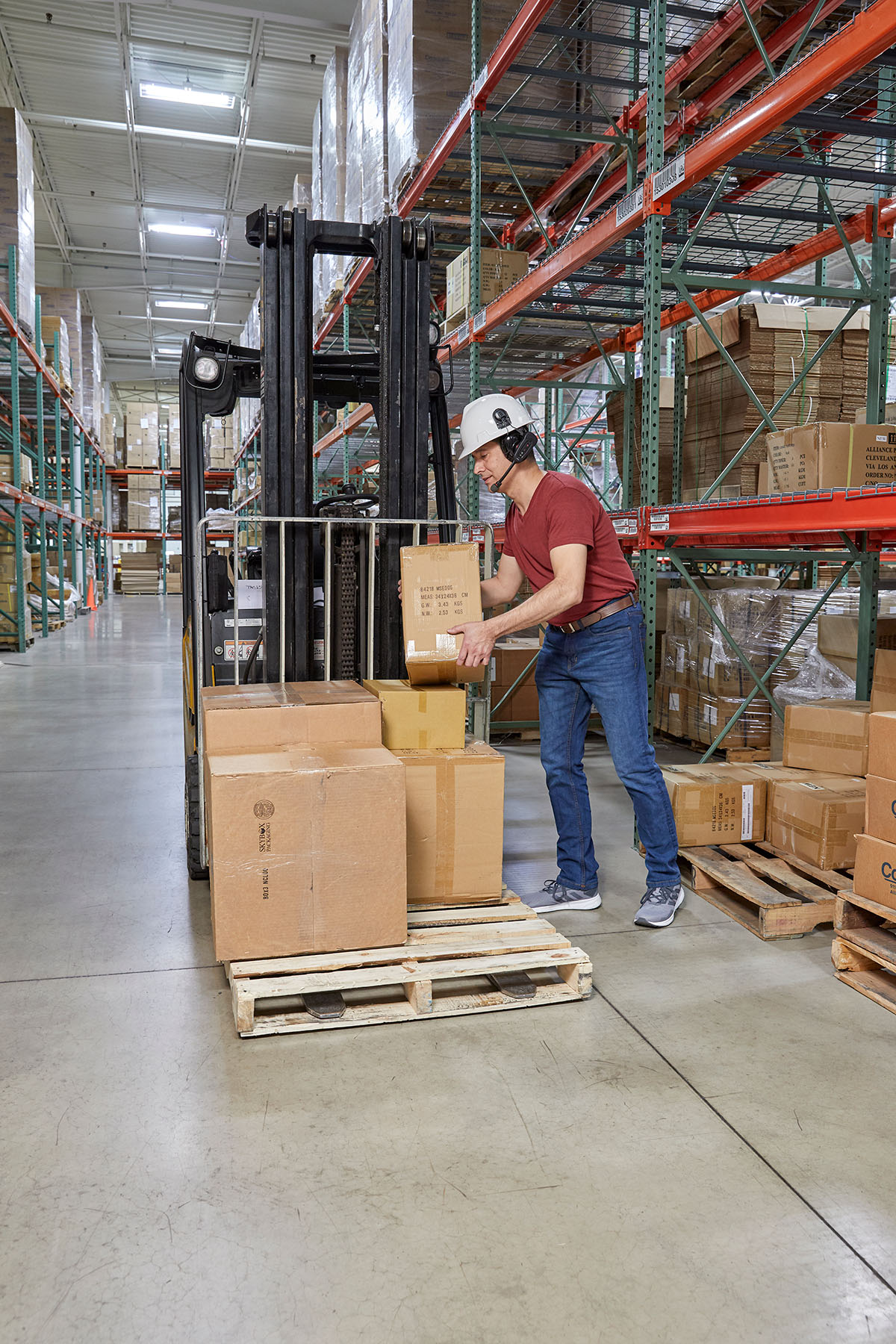 Pracownik magazynu kompletuje opakowania na palecie z wykorzystaniem technologii Voice Picking