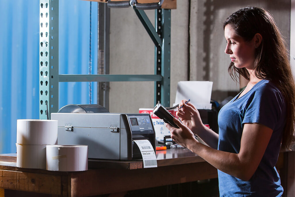 Pracownik magazynu drukujący etykietę wysyłkową z drukarki etykiet