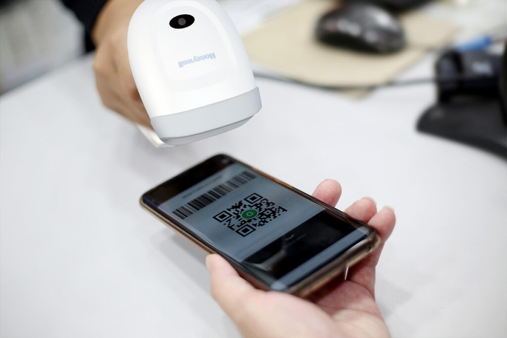 Pracownik sklepu skanuje kod QR klienta skanerem Honeywell Voyager 1350G
