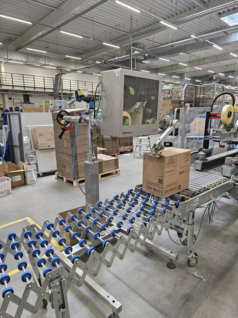 Aplikator CAB Hermes Q – etykietowanie kartonów na przenośniku w magazynie