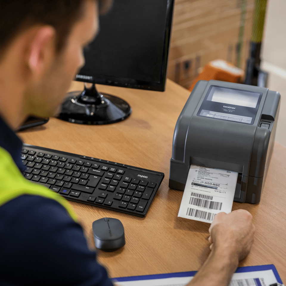 Pracownik magazynu odbiera wydrukowaną etykietę z drukarki samoprzylepnej