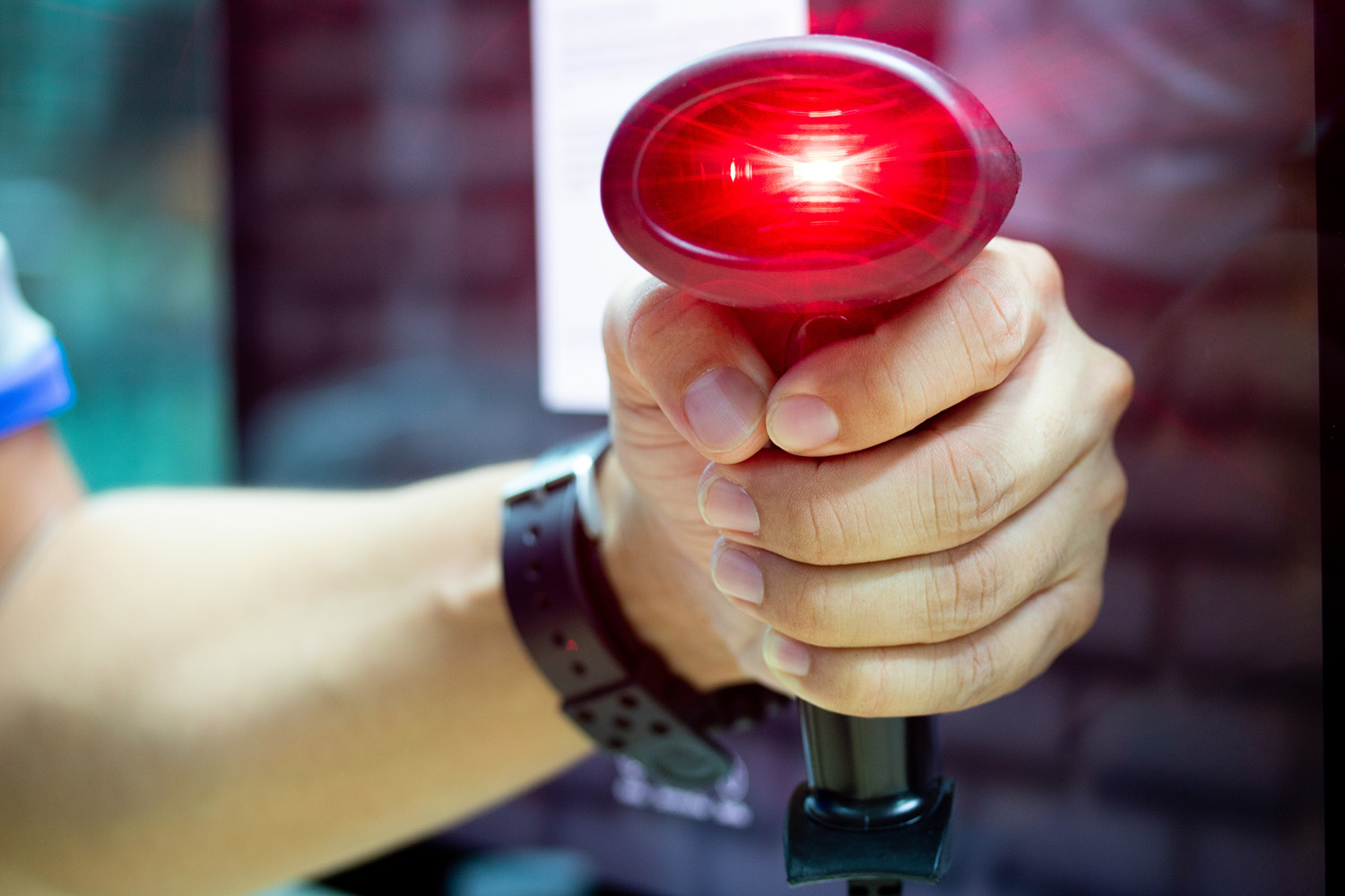 Skaner kodów kreskowych AutoID trzymany w ręku z widoczną wiązka lasera w trakcie skanowania