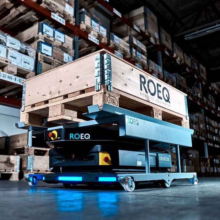 Robot AMR z akcesorium marki ROEQ w magazynie przewożący paletę
