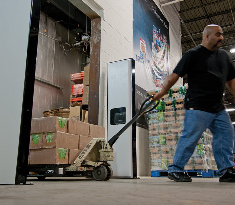 Zdjęcie bramki RFID Zebra - pracownik ciągnie wózek z towarem