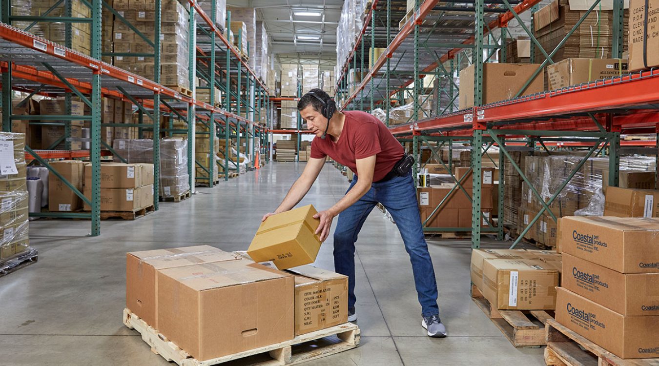 Honeywell-voice2 Pracownik odkładający towar na paletę używający urządzenia do komunikacji głosowej firmy Honeywell