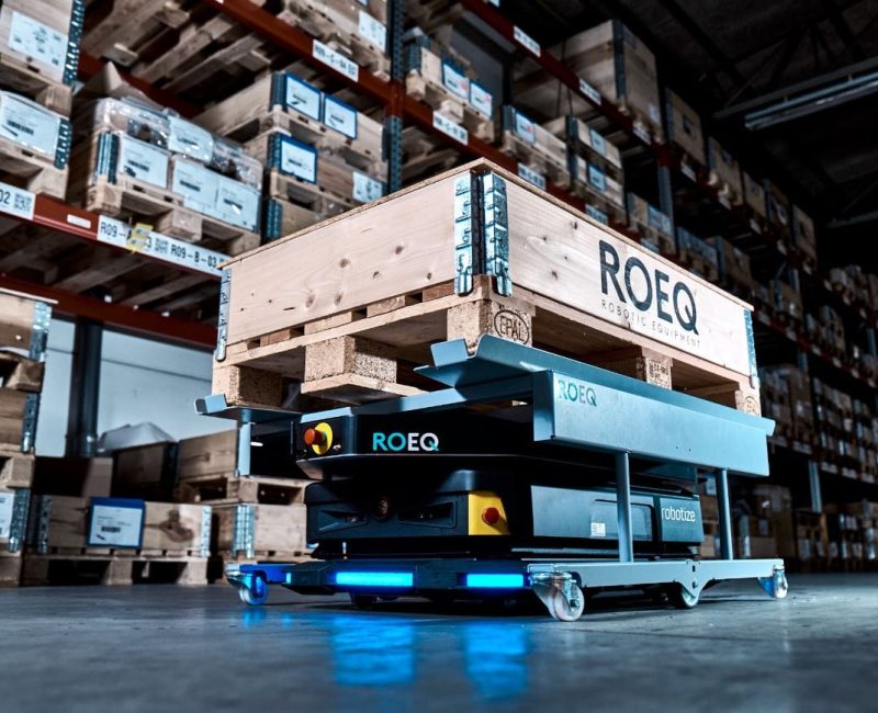 Robot AMR z akcesorium marki ROEQ w magazynie przewożący paletę