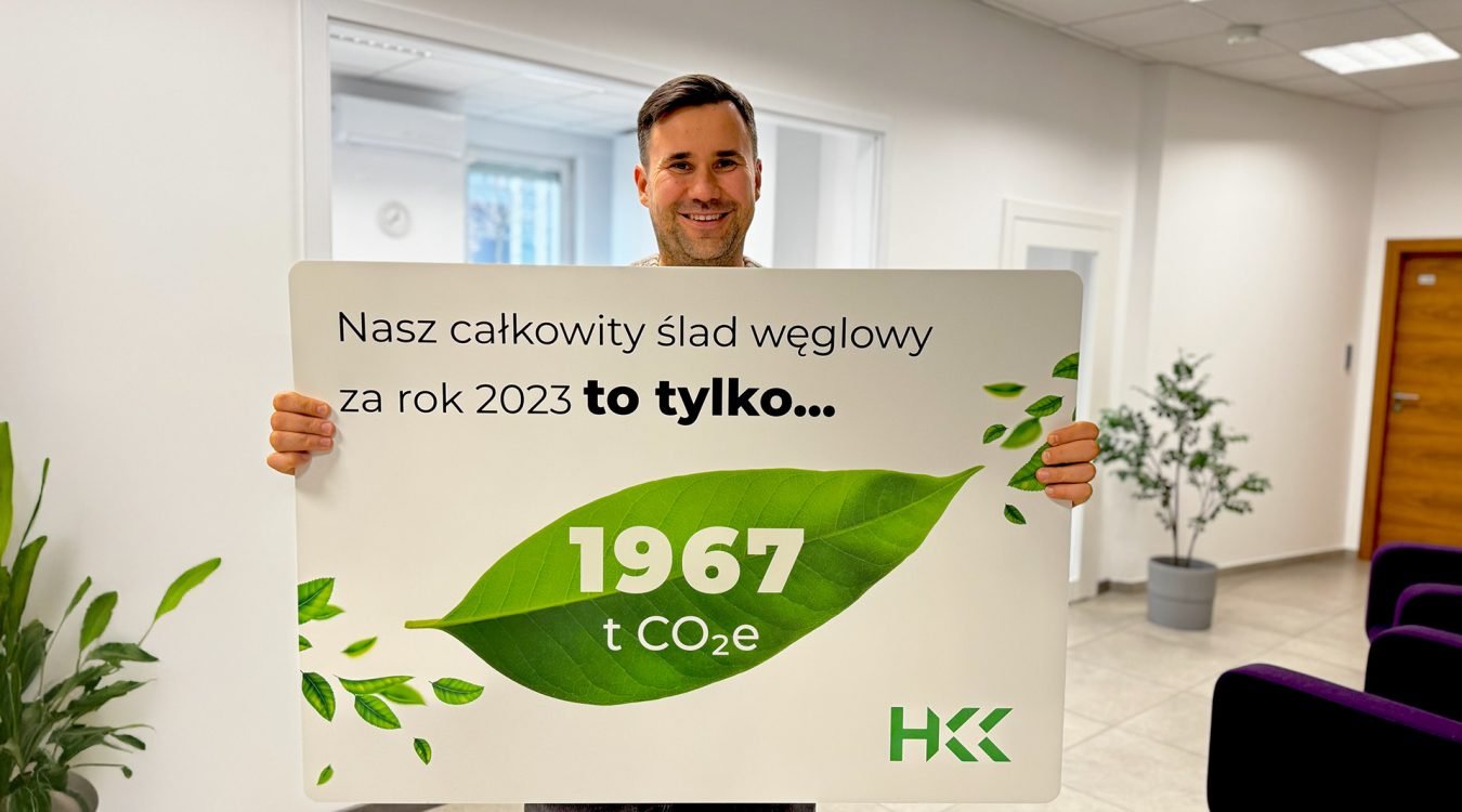 Jędrzej Iglewski – członek zarządu HKK Group z tablicą infograficzną o zmniejszeniu śladu węglowego w 2023 roku