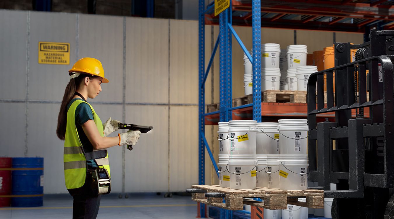 Pracownik magazynu skanujący kod kreskowy na wiadrach z farbą