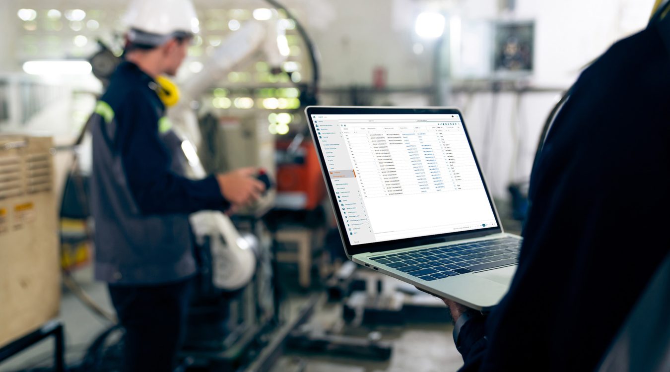 Laptop z systemem Digital Twin Digitio Factory trzymany przez pracownika – w tle hala produkcyjna
