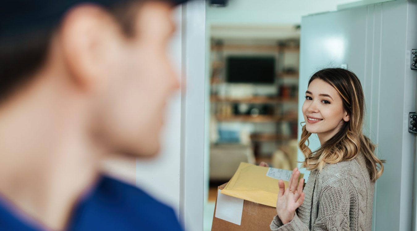 Uśmiechnięta kobieta żegnająca kuriera – dostawa przesyłki